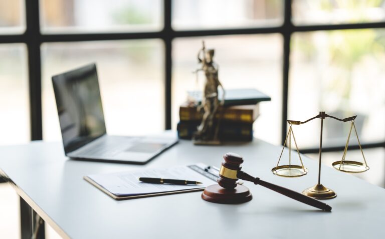 law firm courtroom Law books, computer and scales of justice on table in lawyer office