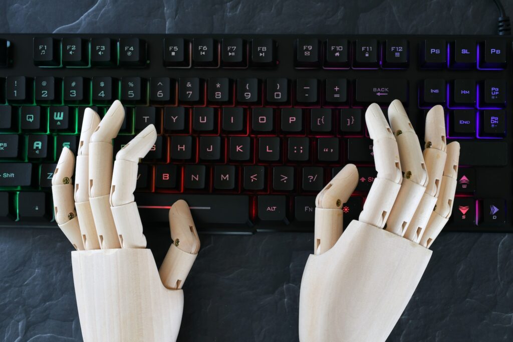 ai artificial intelligence concept robot hands typing on lit keyboard