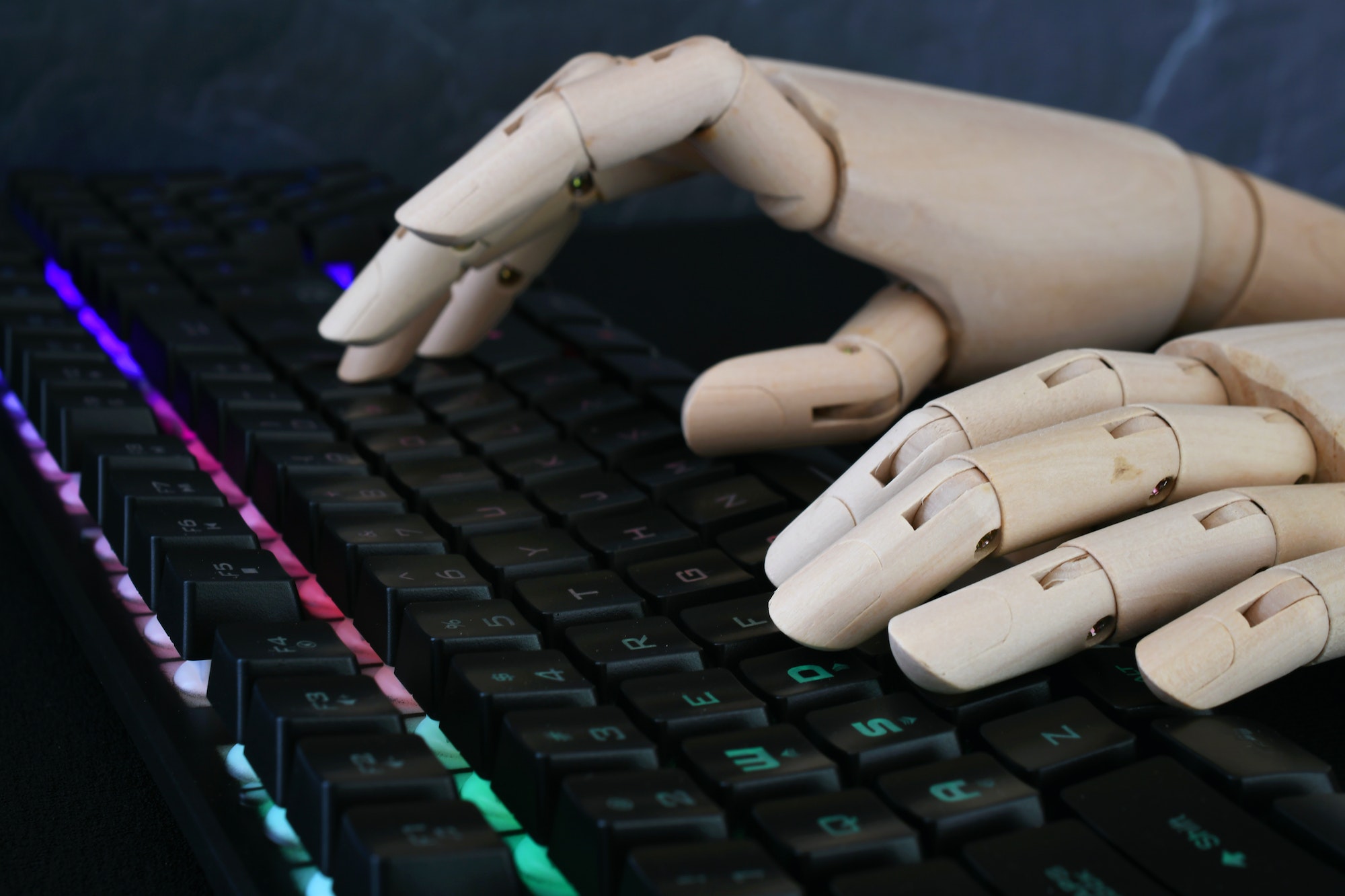 ai artificial intelligence concept robot hands typing on lit keyboard