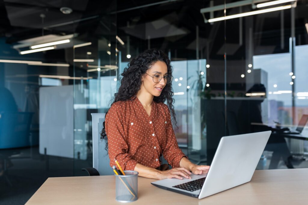 Cheerful and successful indian woman programmer at work inside modern office, tech support worker