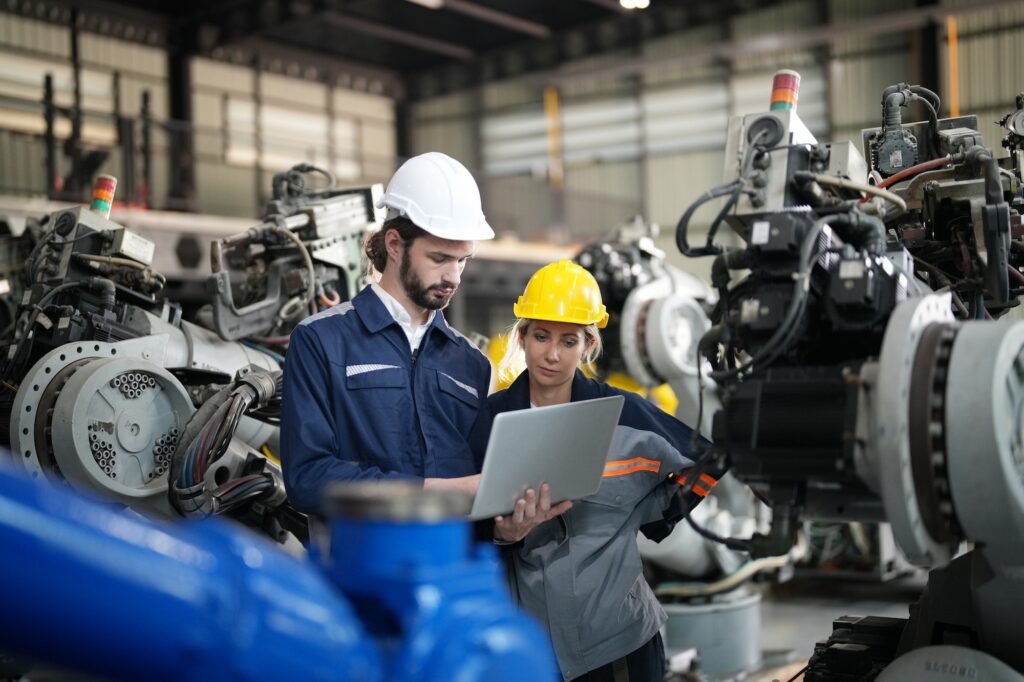 Engineer inspecting automatic AI robot arm and machines in factory. Engineer inspecting automatic AI