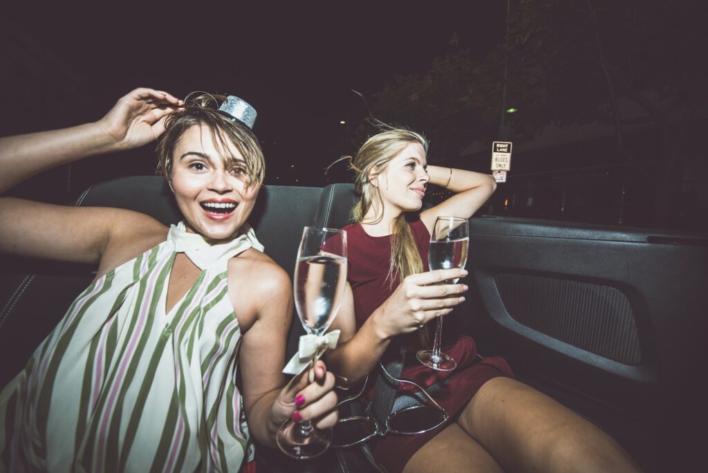 Party girls celebrate in Hollywood drinking champagne on a covertible car