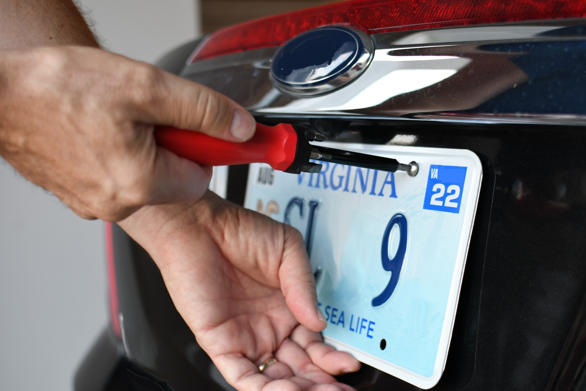 Using tools to attach vehicle registration license plate to car so it is legal to drive on road