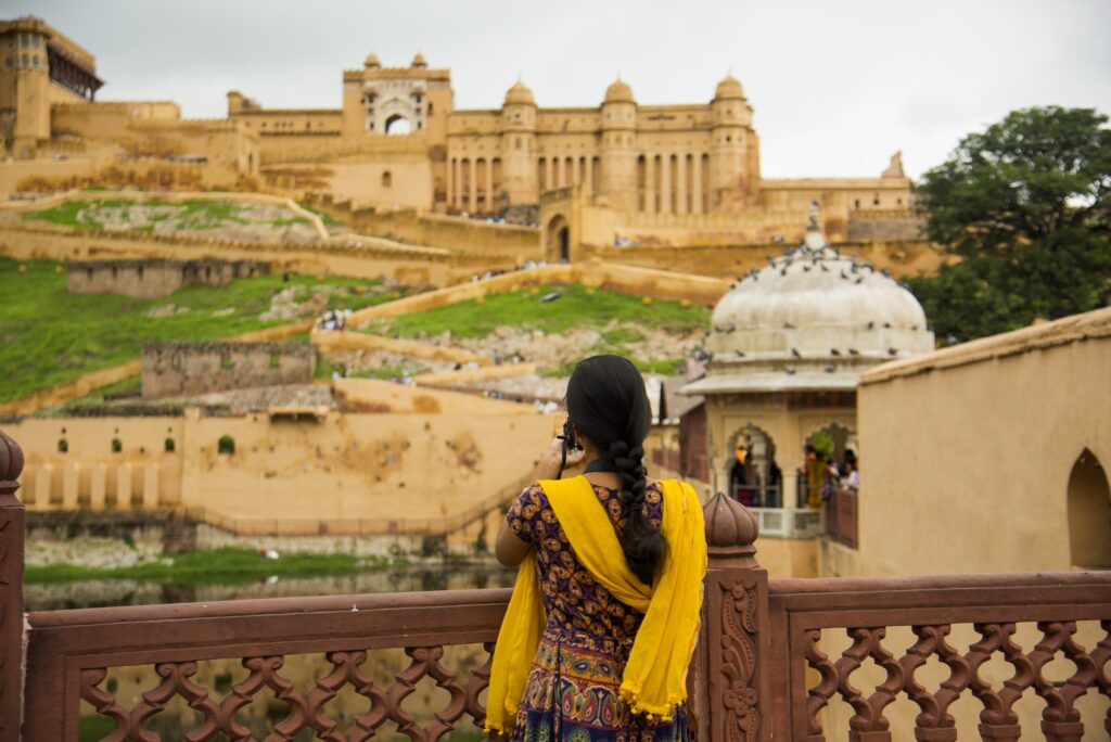 Woman tourist taking a photo of the Amer fort, located in Jaipur, India.