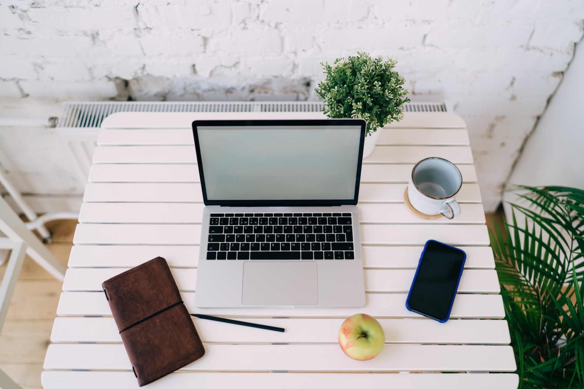 Workplace with devices placed near cup and apple on table