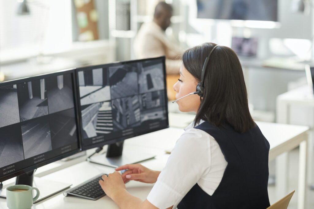 Young woman looking at surveillance camera feeds in security office