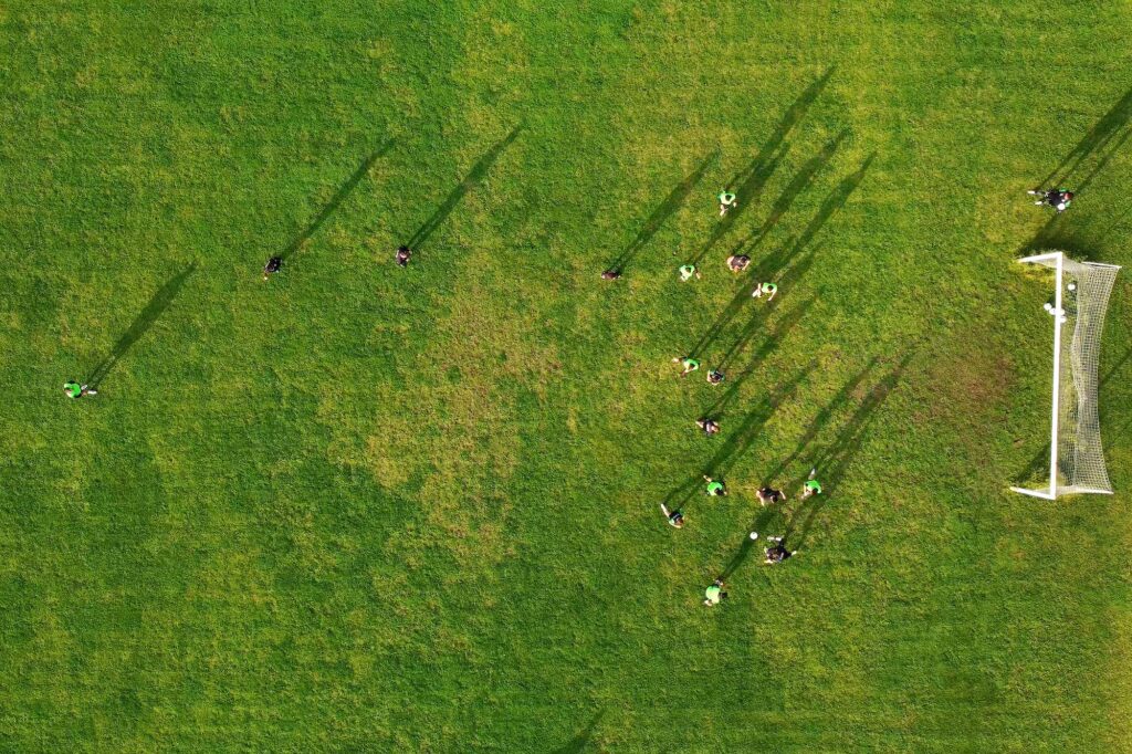 Aerial drone view of a sports field and a football team that practices tactical schemes.