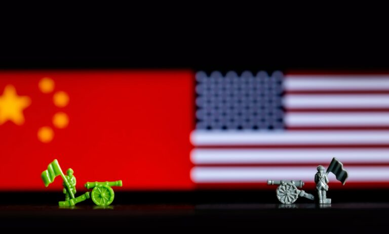 Closeup of toy war figurines on background of the Chinese and US flags depicting the trade war