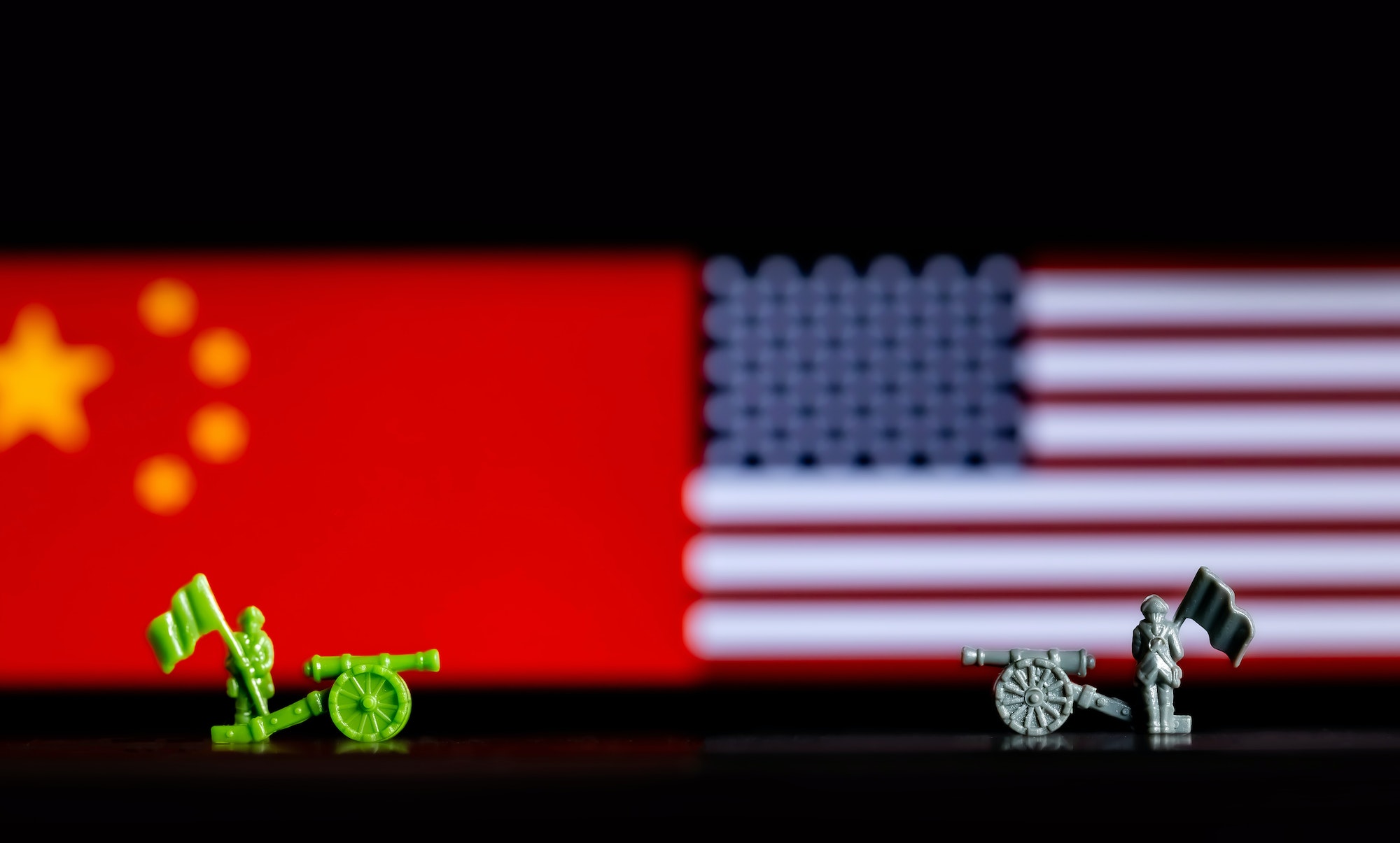 Closeup of toy war figurines on background of the Chinese and US flags depicting the trade war