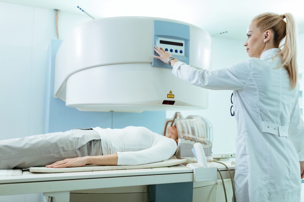 Female radiologist starting MRI scan of the patient's brain at clinic.