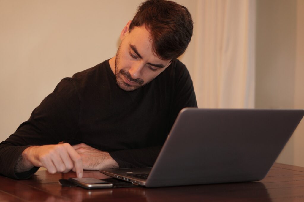 Handsome young man with smartphone and laptop