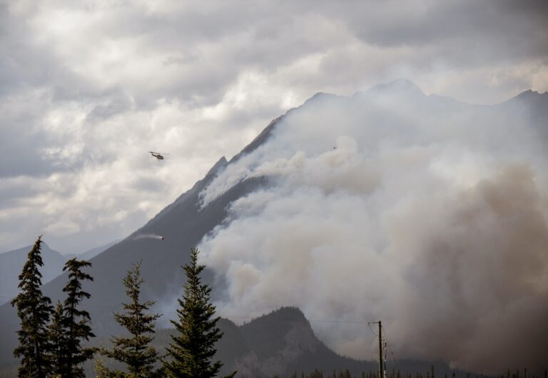 Helicopter with water bucket flies into thick wildfire smoke