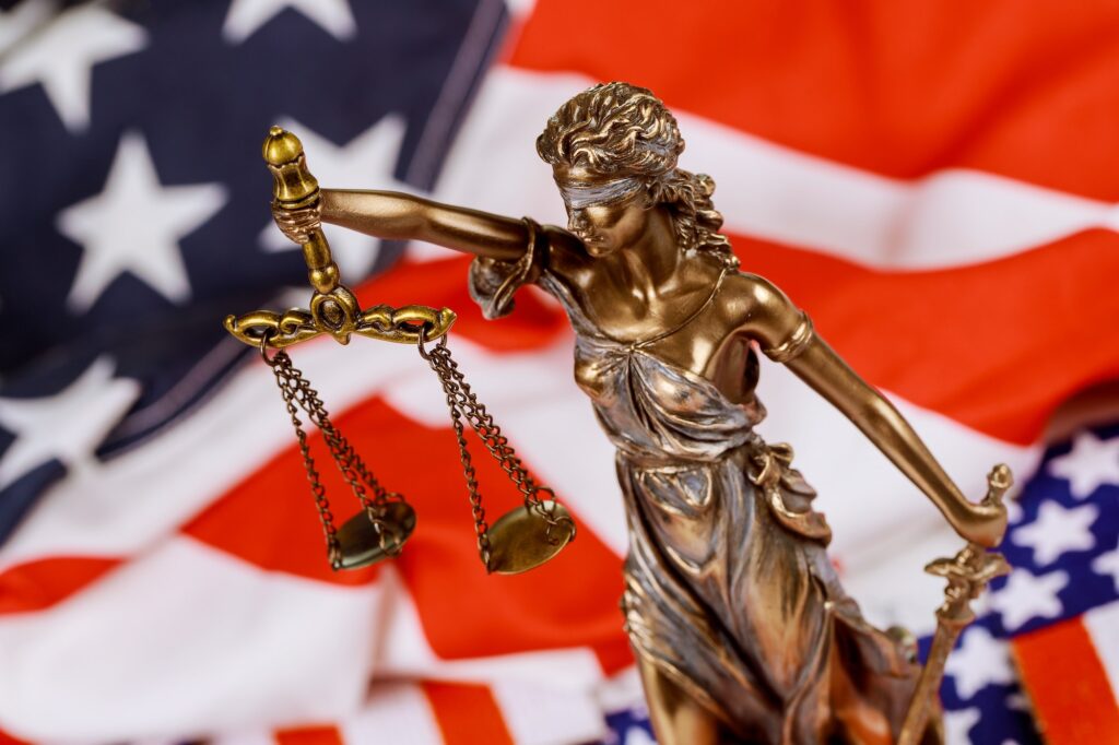 Lawyers desk statue of justice on law court in United States of America flag in background