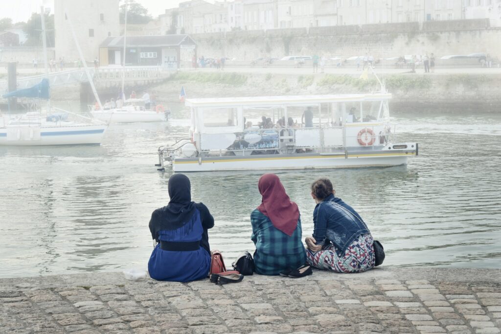 Muslim woman wearing hijab looking on the ocean and yachts at La Rochelle, France.