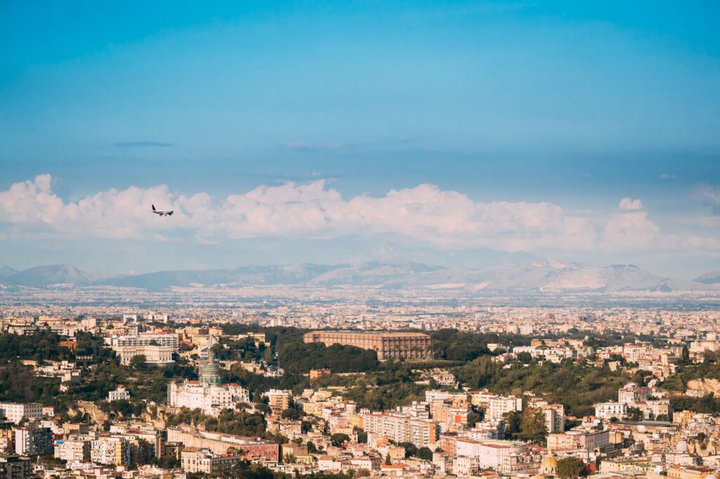 Naples, Italy. Plane Flying Above City. Top View Of Cityscape