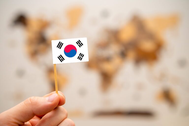 South Korean flag in mans hand on the world map background.