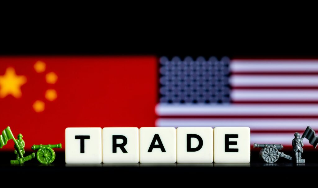 Word "Trade" made of tiles next to military miniatures on blurred China and US flags background