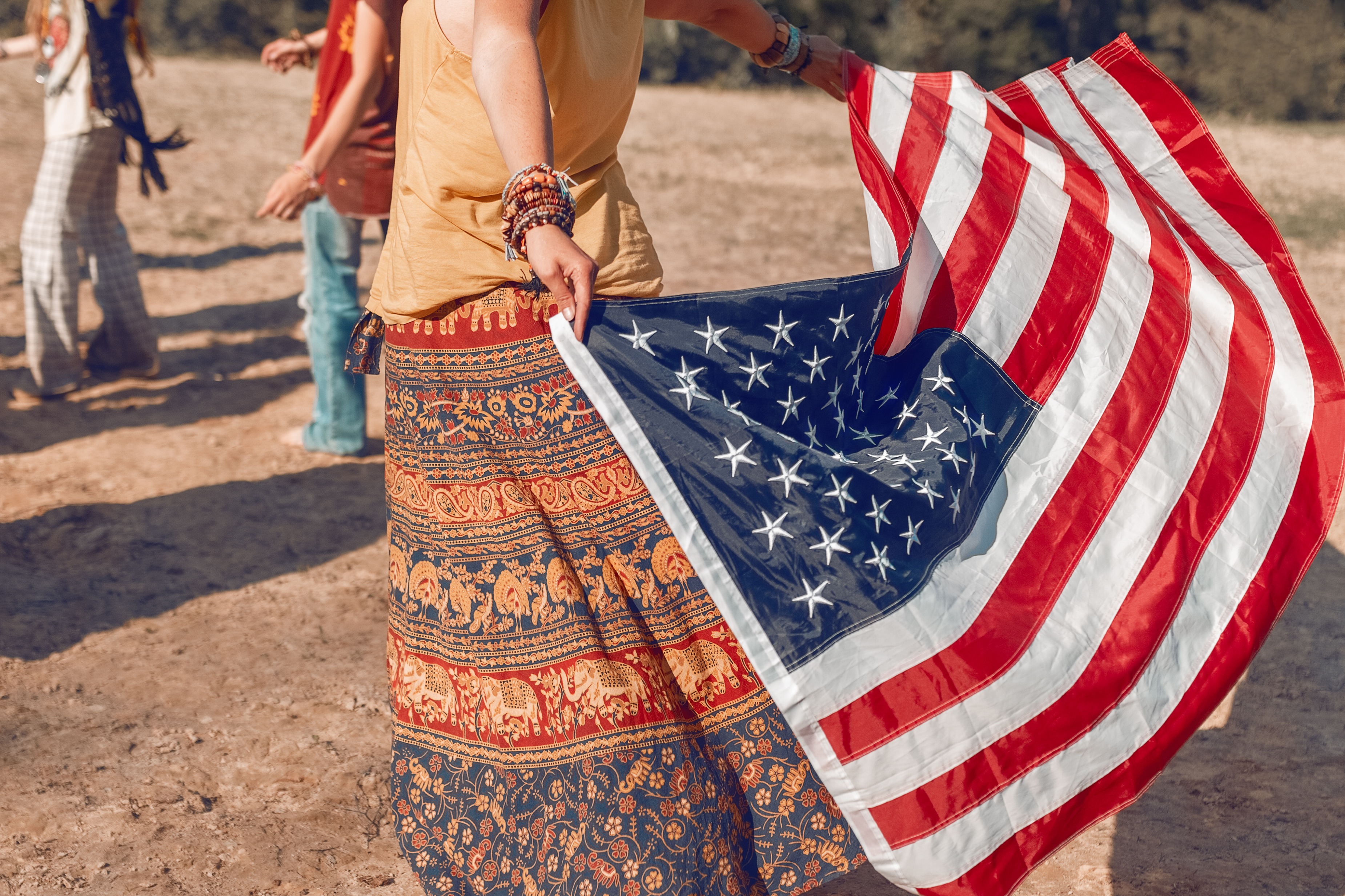 american flag in hands of dancing hippie girl in ethnic costume on summer day