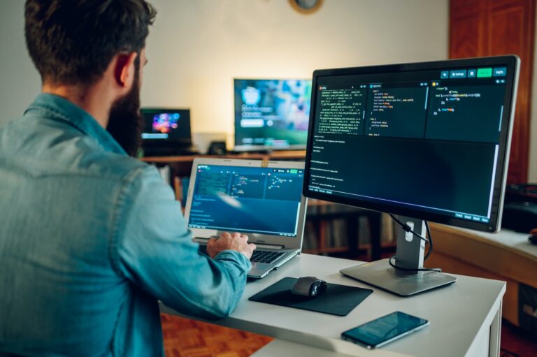 Rear view of an IT expert working on AI generators and AI bots at his home office by writing code.