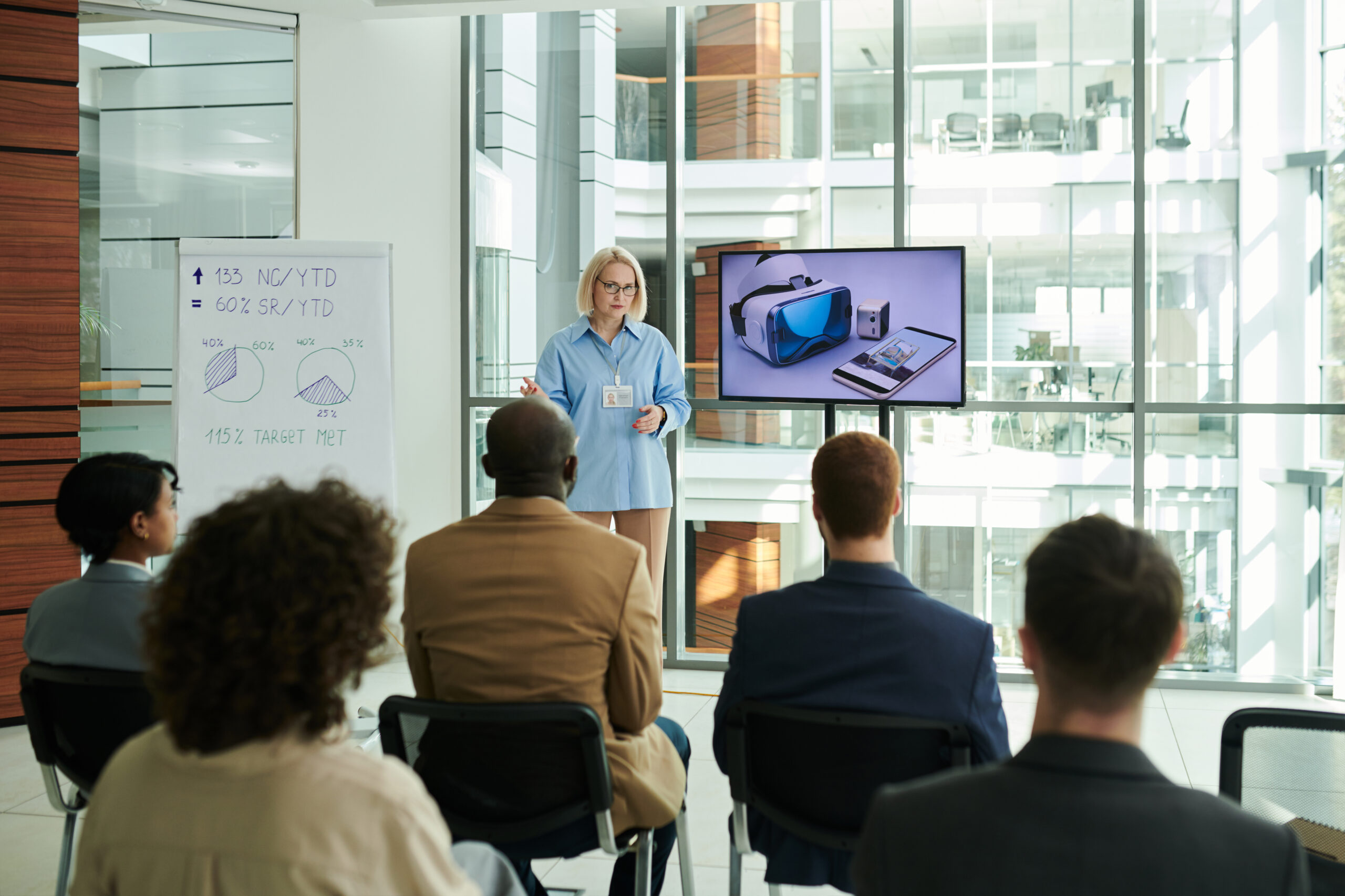 rear view of young audience listening to mature female coach at seminar