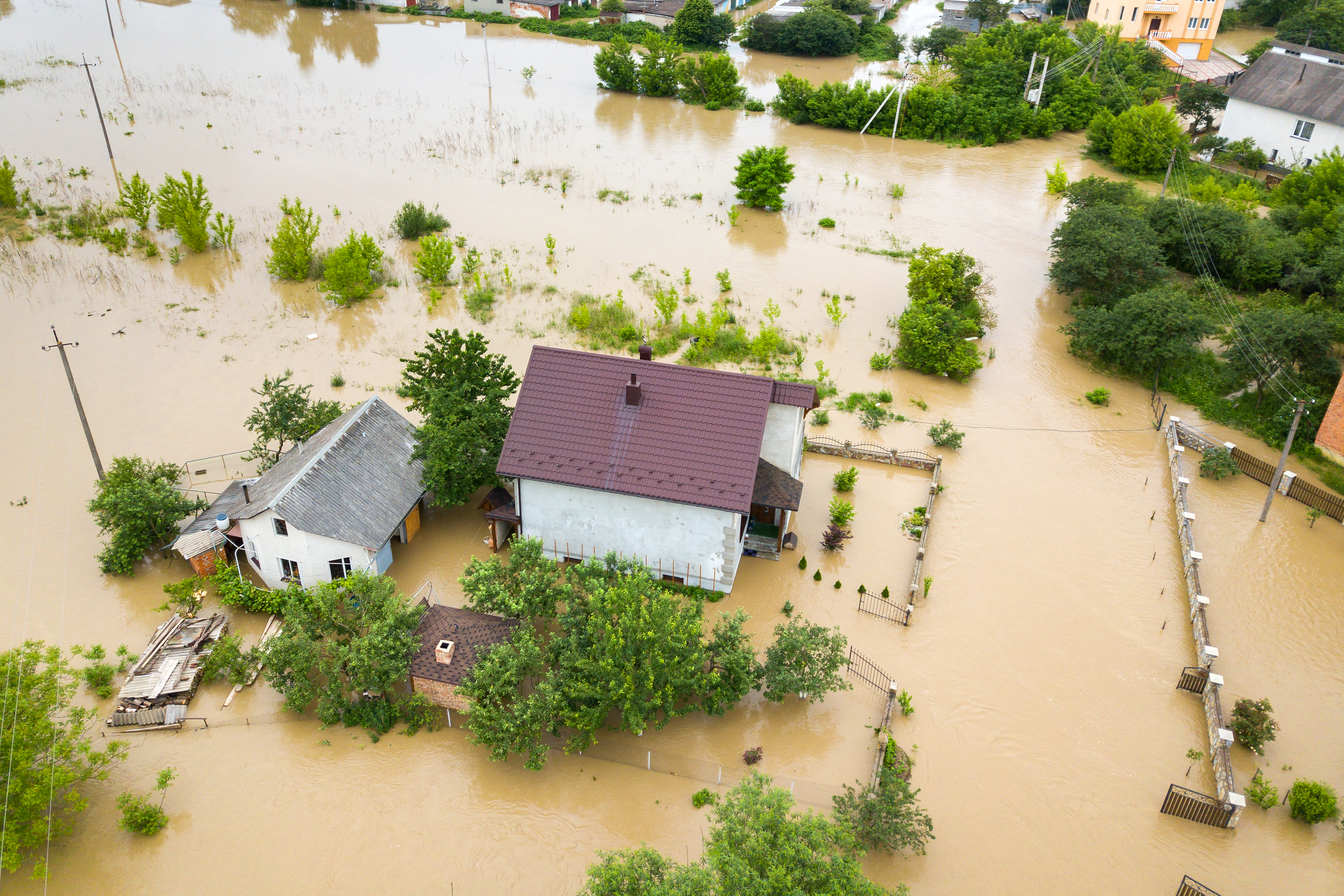 Aerial view of flooded house with dirty water all around it.