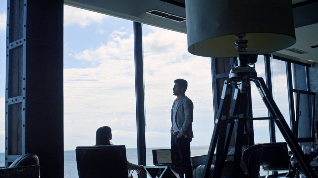 Business team silhouettes talking at sea clouds view. Two managers work laptop