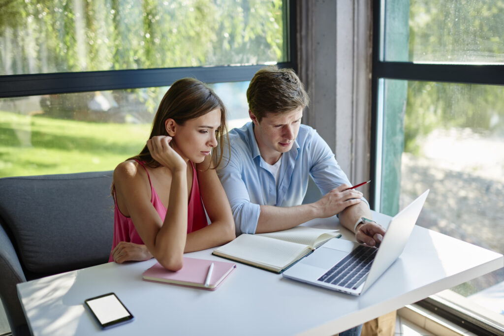 Caucasian man and woman discussing web content while e learning in coworking