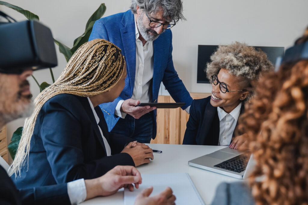 Multiracial business people using virtual reality goggles while work inside office - Metaverse techn