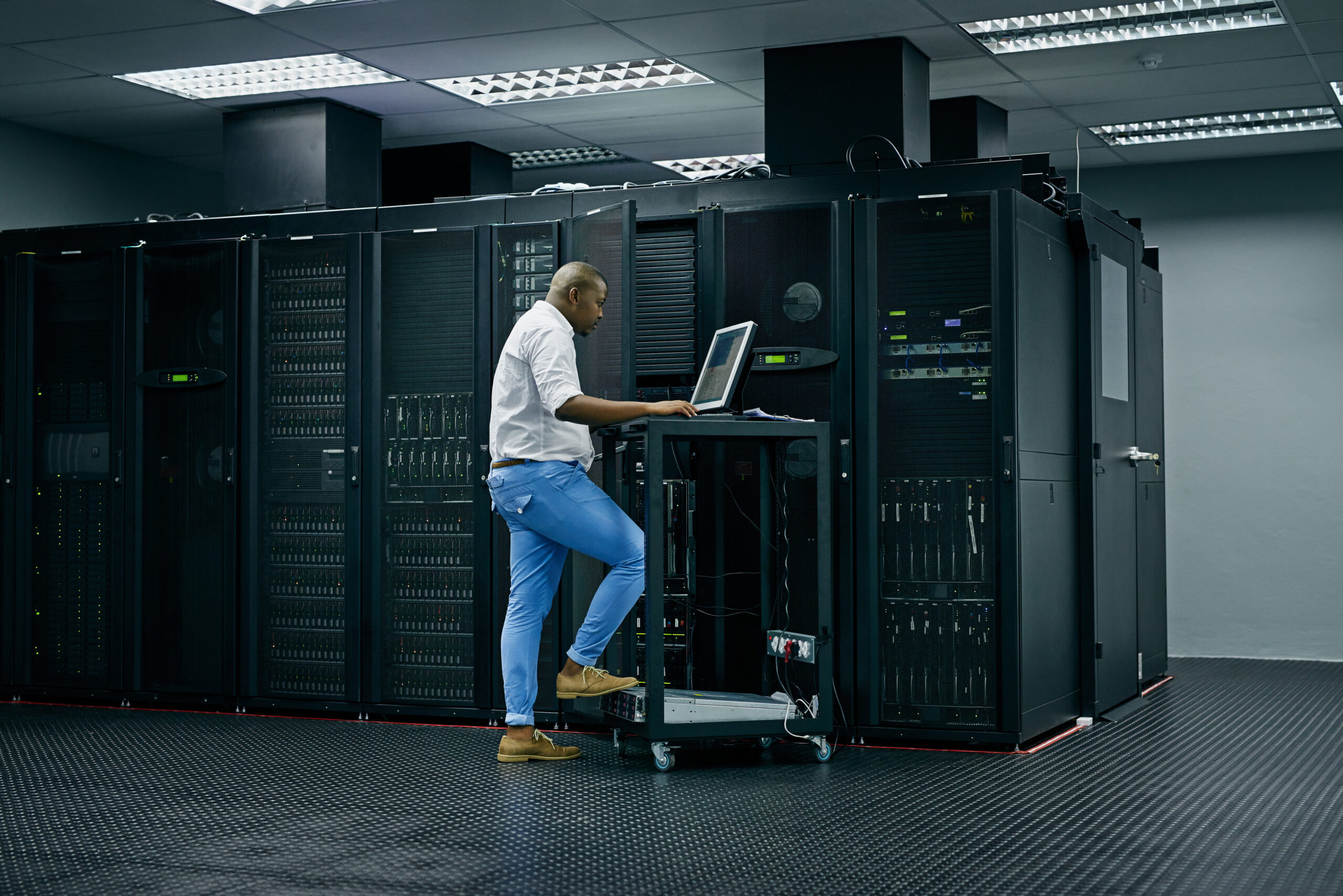 skilled in all things it shot of an it technician using a computer while working in a data center