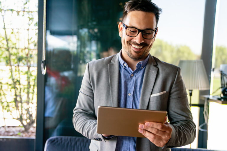 Young smiling successful business man, entrepreneur in formal business suite working on tablet