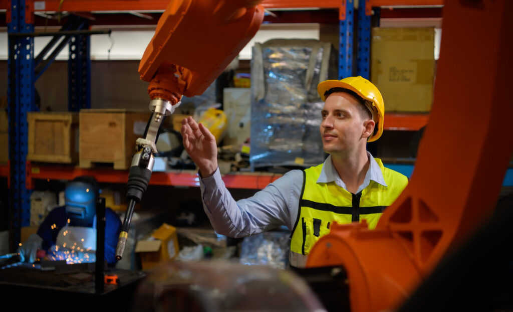 A male engineer checking the operation of a welding robot.