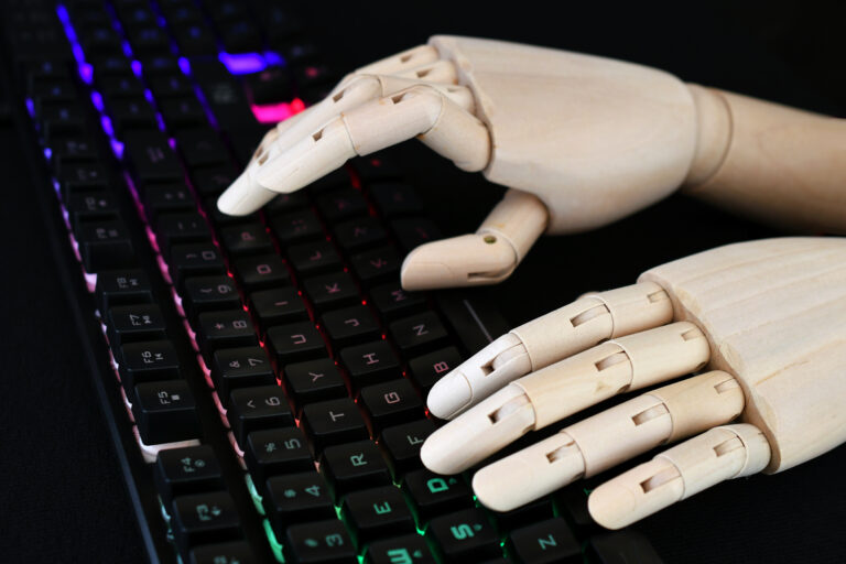 AI artificial intelligence concept - robot hands typing on lit keyboard