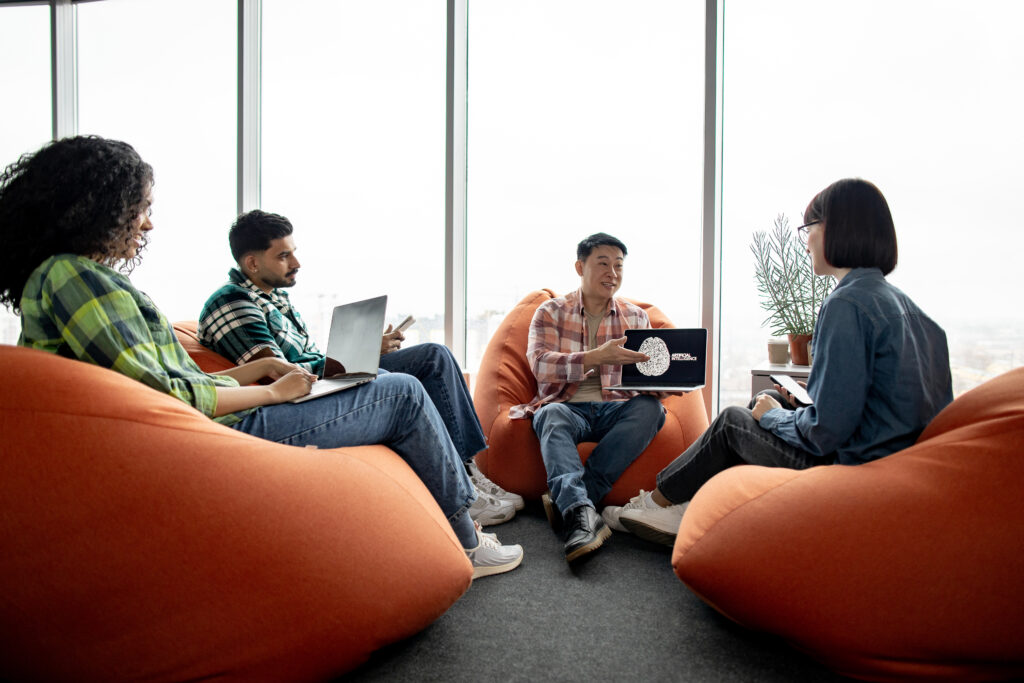 Male with AI project on laptop chatting with teammates