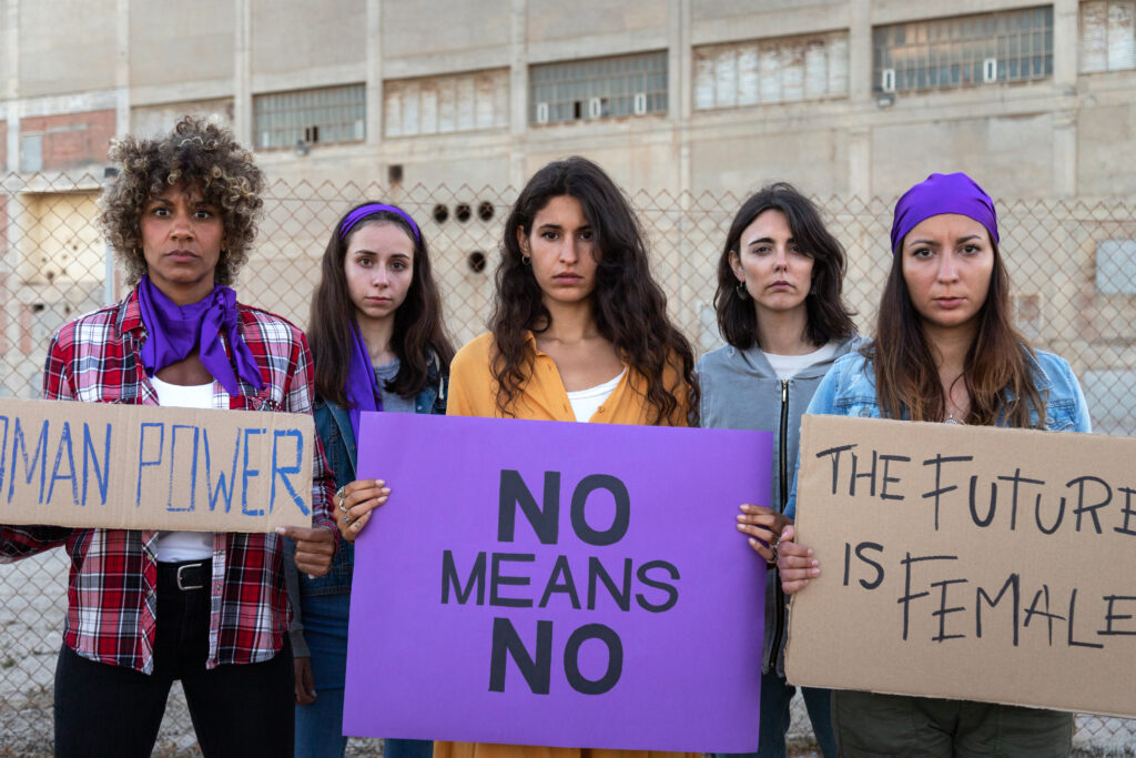 Multi-ethnic women looking at camera stand together protesting for women rights and equality.