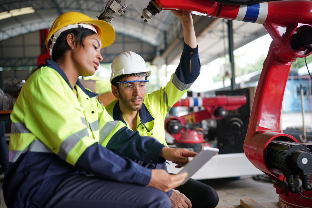 Robotics engineer working on maintenance of robotic arm in factory warehouse. Business technology.