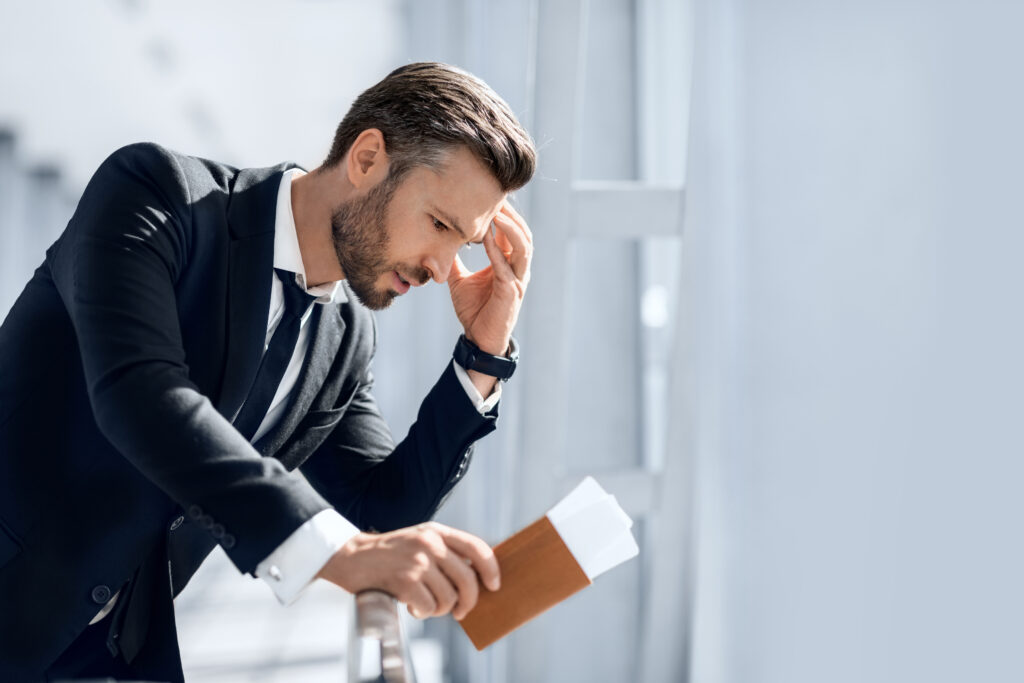 Stressful businessman waiting at airport after flight delays and cancellations