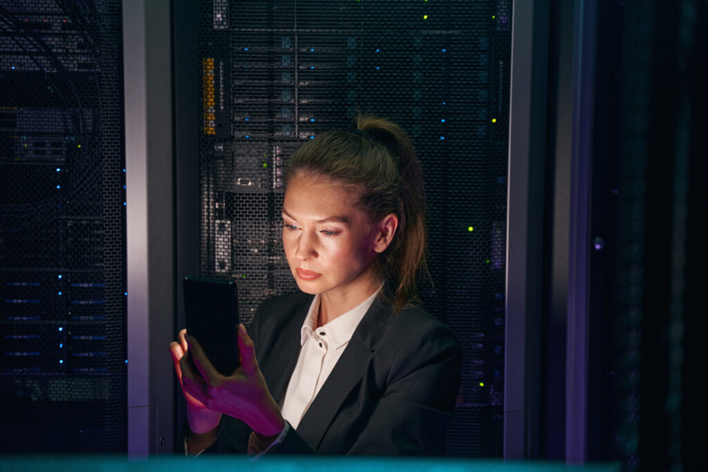 System administrator checking servers with cellphone in data center