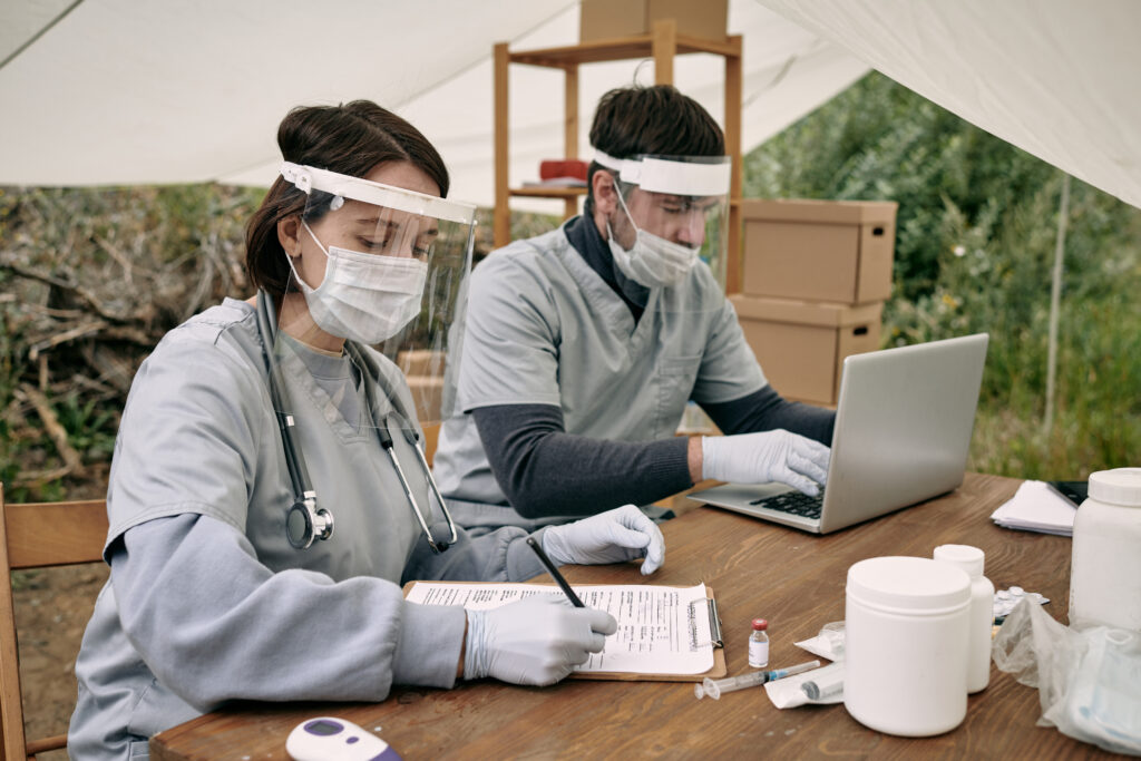 Two young volunteers in medical uniform working in refugee camp