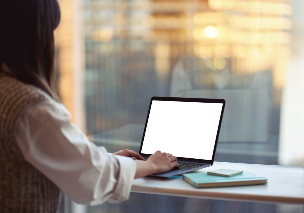 Business woman using laptop at office desk. Over shoulder view, mock up