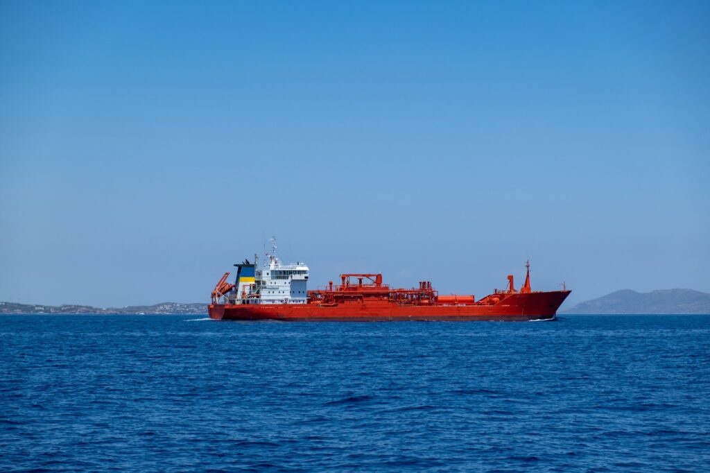 Chemical oil tanker ship, red color in blue Aegean sea and sky background. Greece