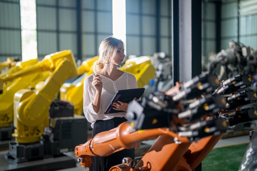 Engineer inspecting automatic AI robot arms and machines in factory.Engineer inspecting automatic AI