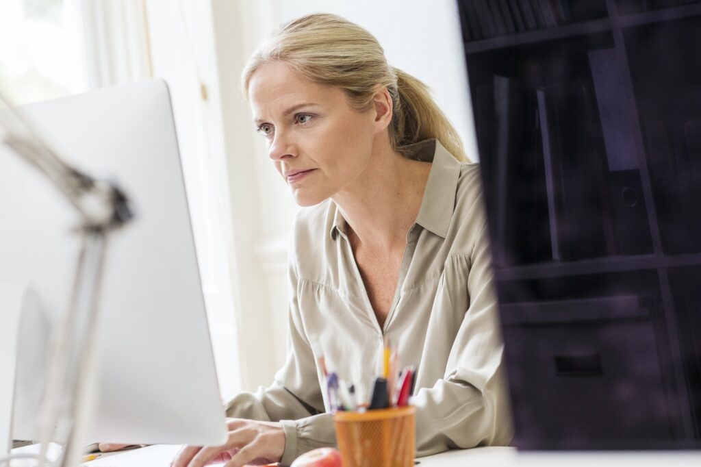 Female designer typing at desktop computer in creative studio