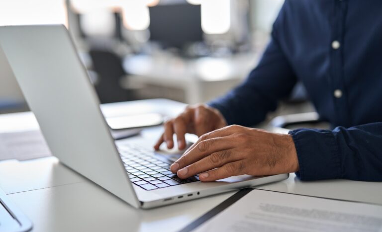 Hands of business man typing on laptop working with ai solutions on computer.