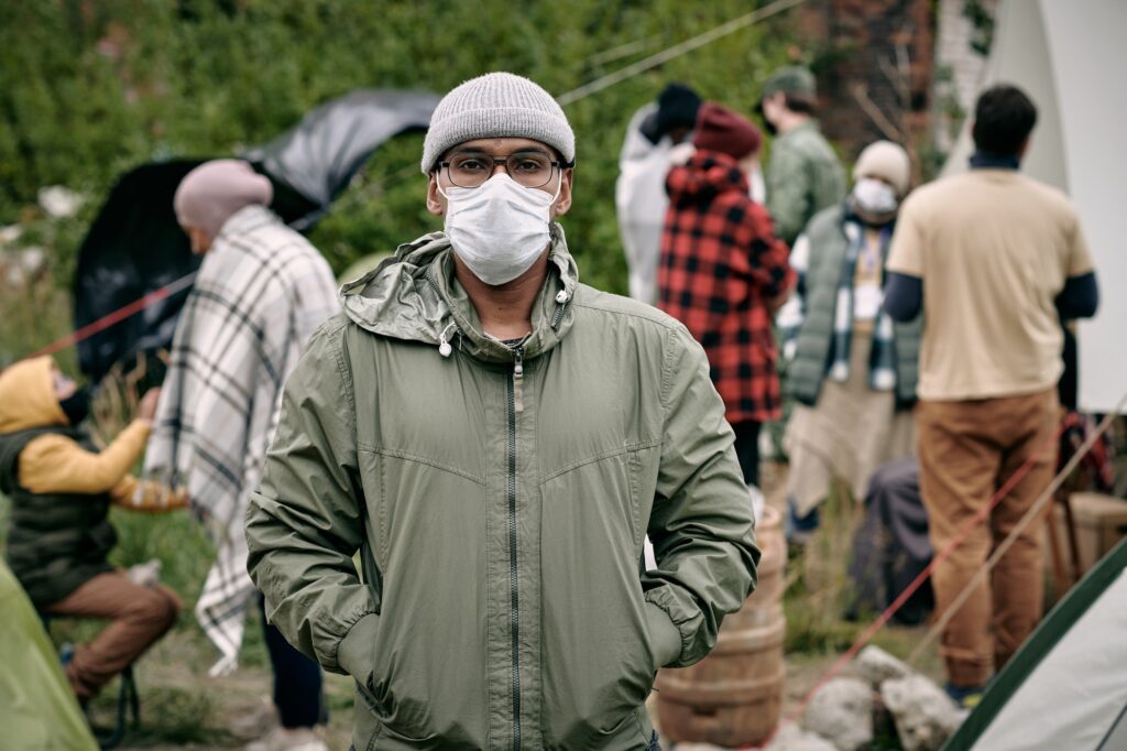 Man In Mask Against Crowd Of Migrants