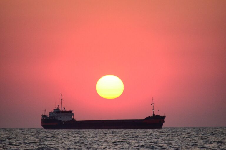 over a cargo ship in the sea, the red sun rises