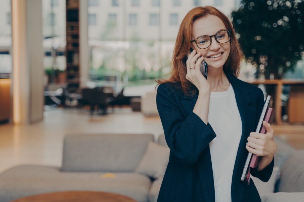 Portrait of attractive positive european business woman having mobile conversation