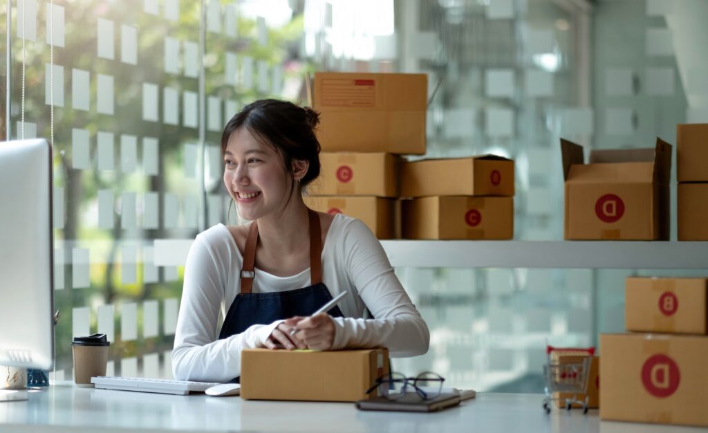 Asian Small business entrepreneur SME writing address on cardboard box at workplace small business