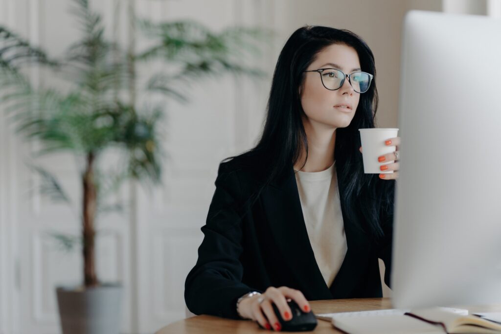 Busy admin, sipping coffee, dresses formally, strategizing startup at desk, fully engaged