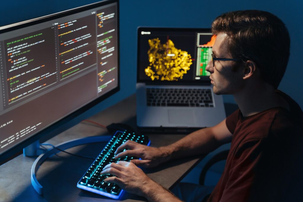 Closeup of program developer writing software on multiple computer screens at home office