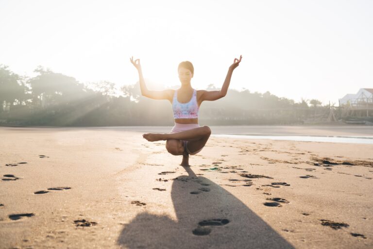 Energetic female trainer doing balance exercises during morning coastline time for physical recreati